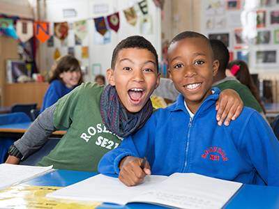 Two boys smiling while reading together.